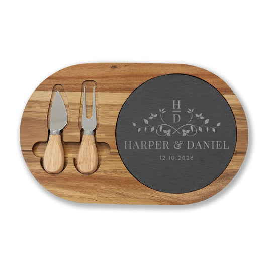 Wooden cutting board with slate center, cheese knife, and fork, personalized with names and date.