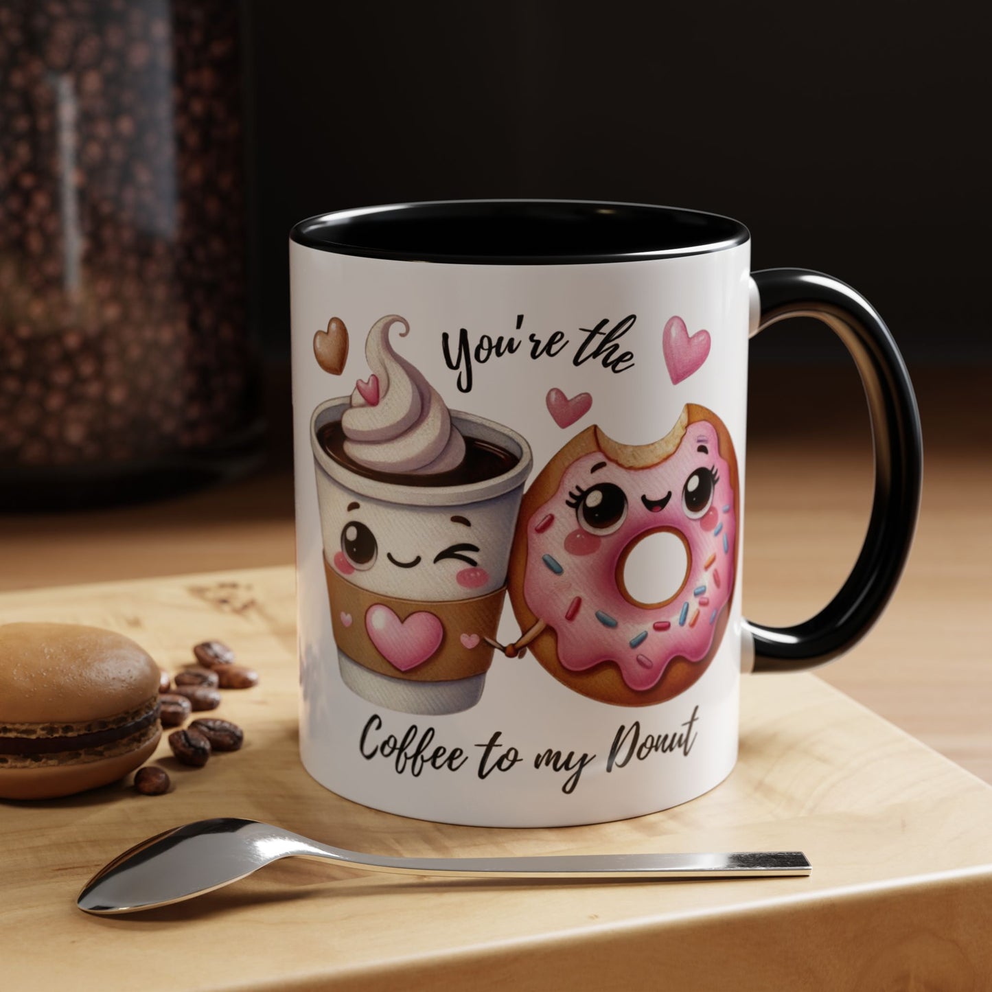 Mug with cartoon coffee cup and donut design on a wooden surface with coffee beans and a spoon. your the coffee to my donut saying
