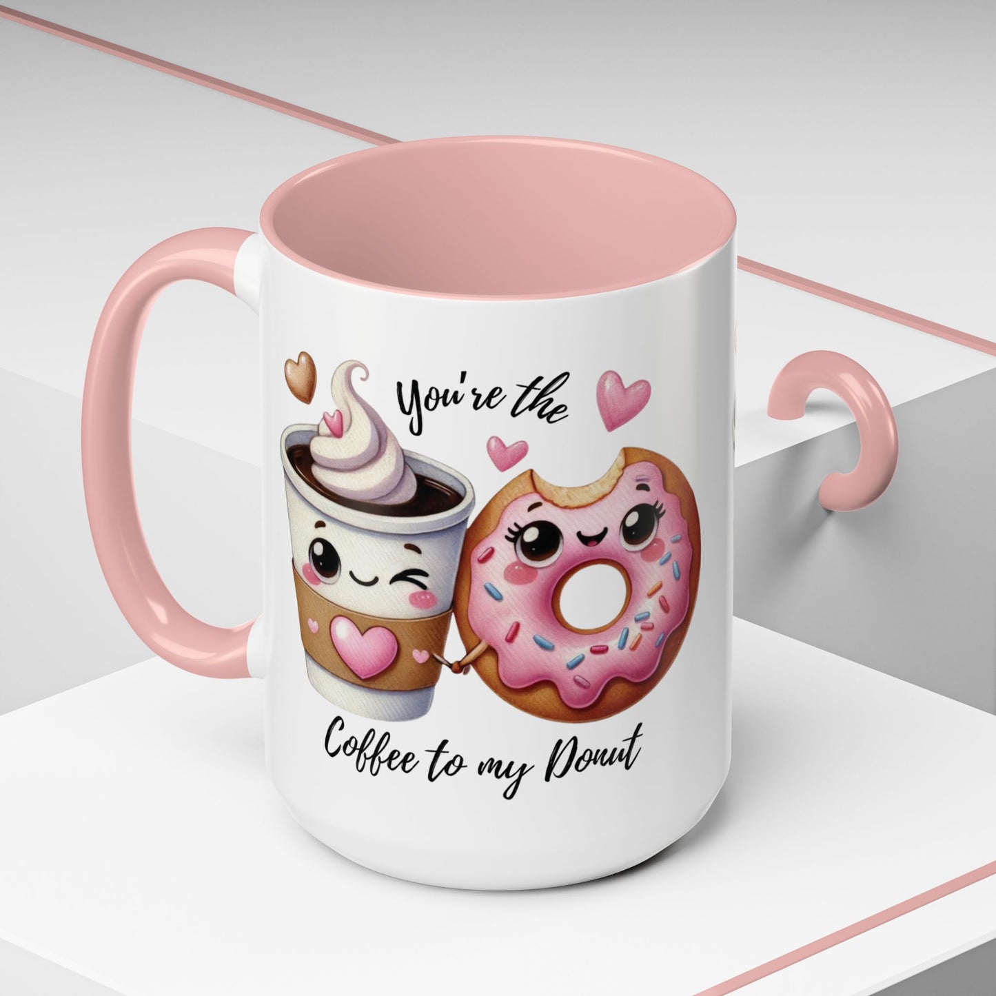 Mug with cartoon coffee cup and donut, text 'You're the coffee to my donut', pink interior and handle.