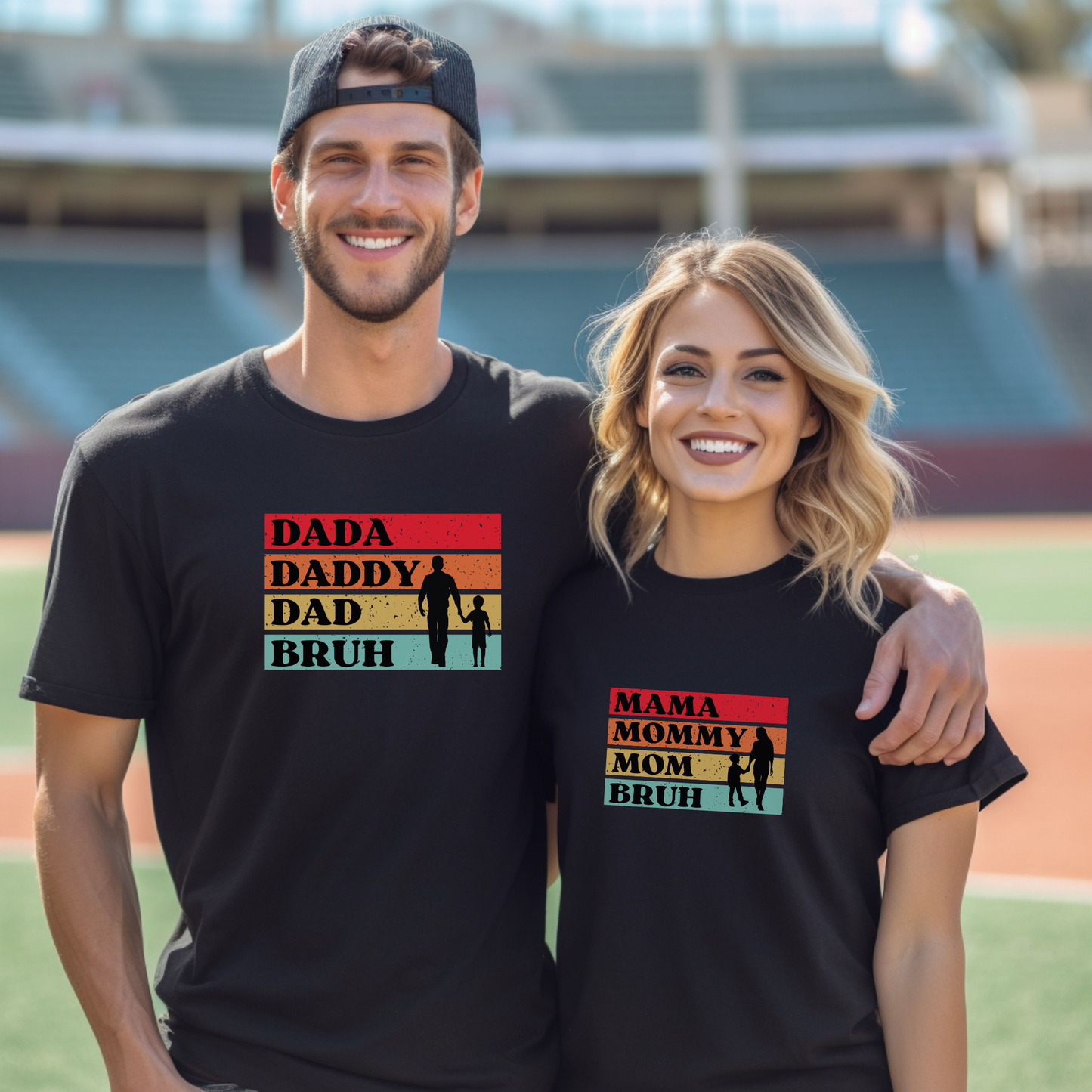 Two people wearing matching black t-shirts with colorful text and graphics on a sports field.