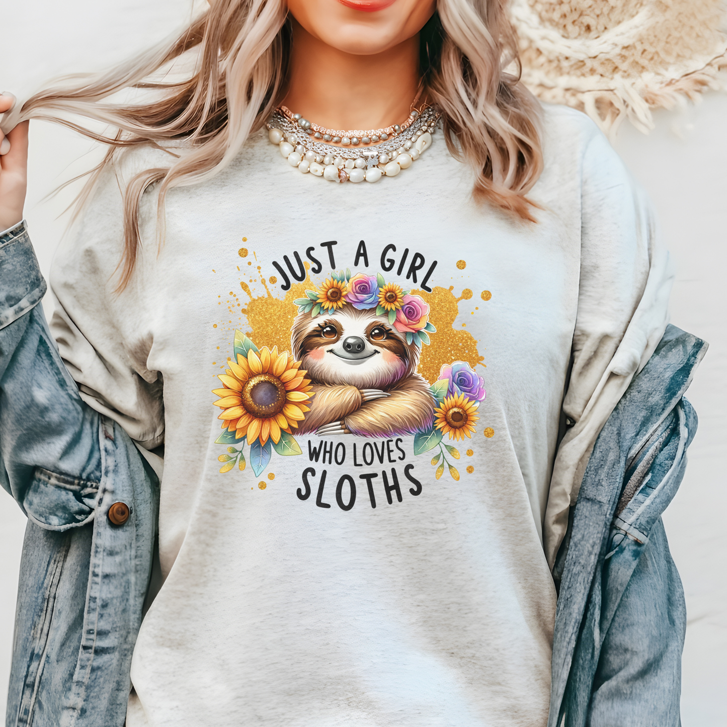 Person wearing a shirt with a sloth graphic and text 'Just a girl who loves sloths' on a plain background