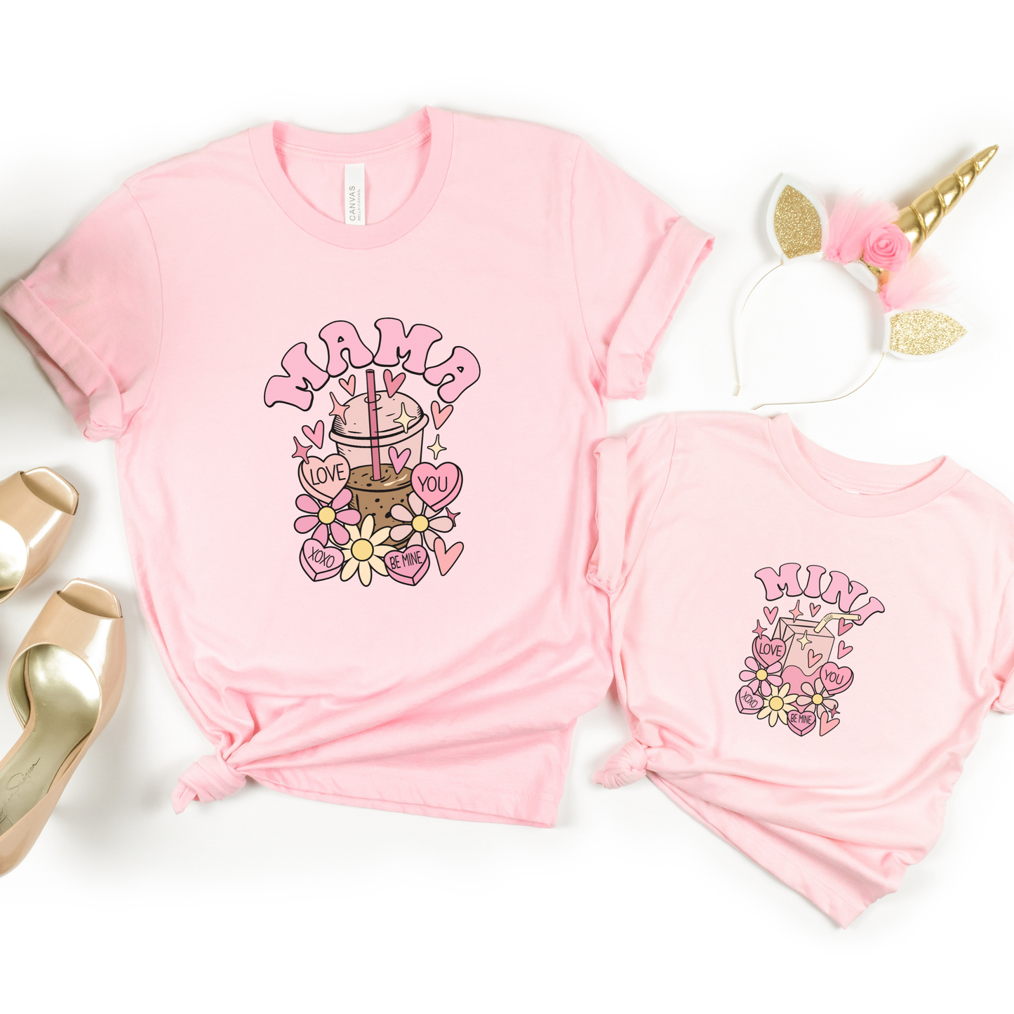 Two pink t-shirts with 'Mama' and 'Mini' graphics on a white background.