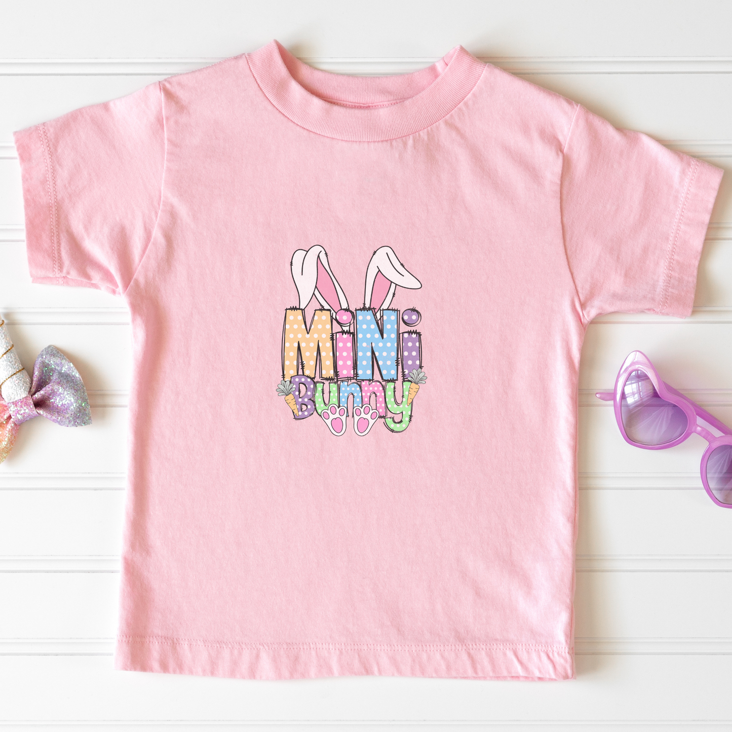 Pink t-shirt with 'Mini Bunny' text and bunny ears graphic on a white background