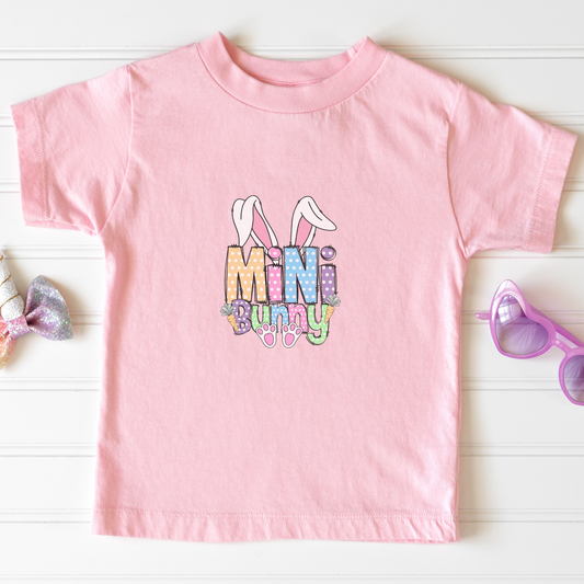 Pink t-shirt with 'Mini Bunny' text and bunny ears graphic on a white background