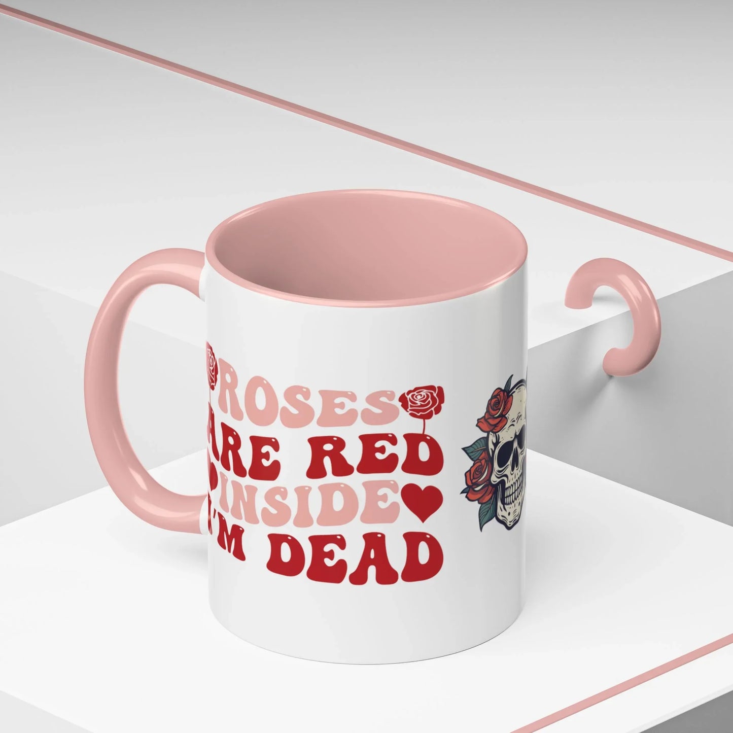 White mug with pink interior and handle, featuring red text and a floral skull design on a white background. roses are red, inside I'm dead, 11oz
