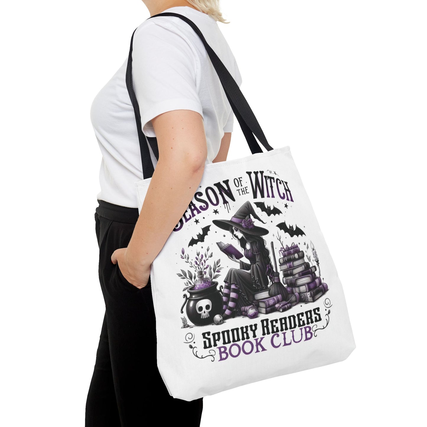 Person holding a tote bag with Halloween-themed design and text. season of the witch spooky readers book club