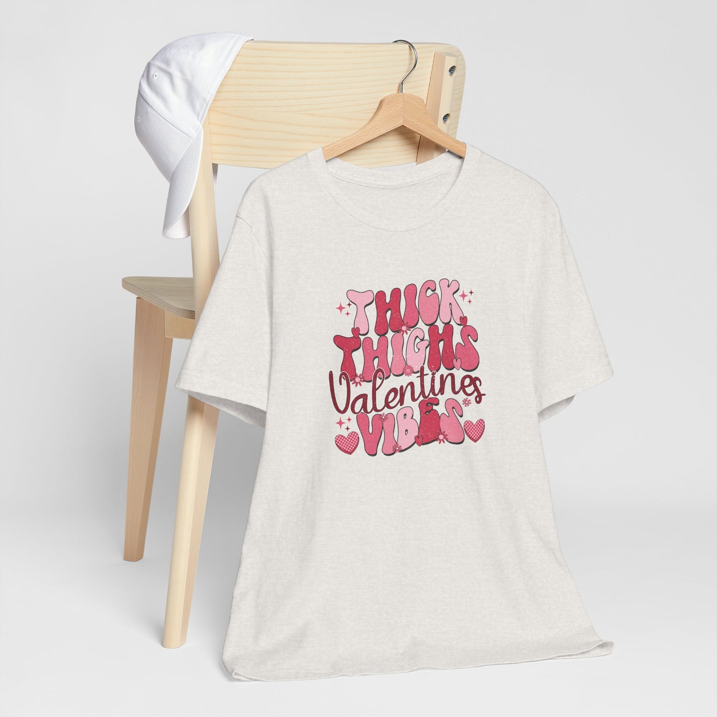 heather cement t-shirt with pink text on a wooden chair against a white background, thick thighs valentines vibes, retro design